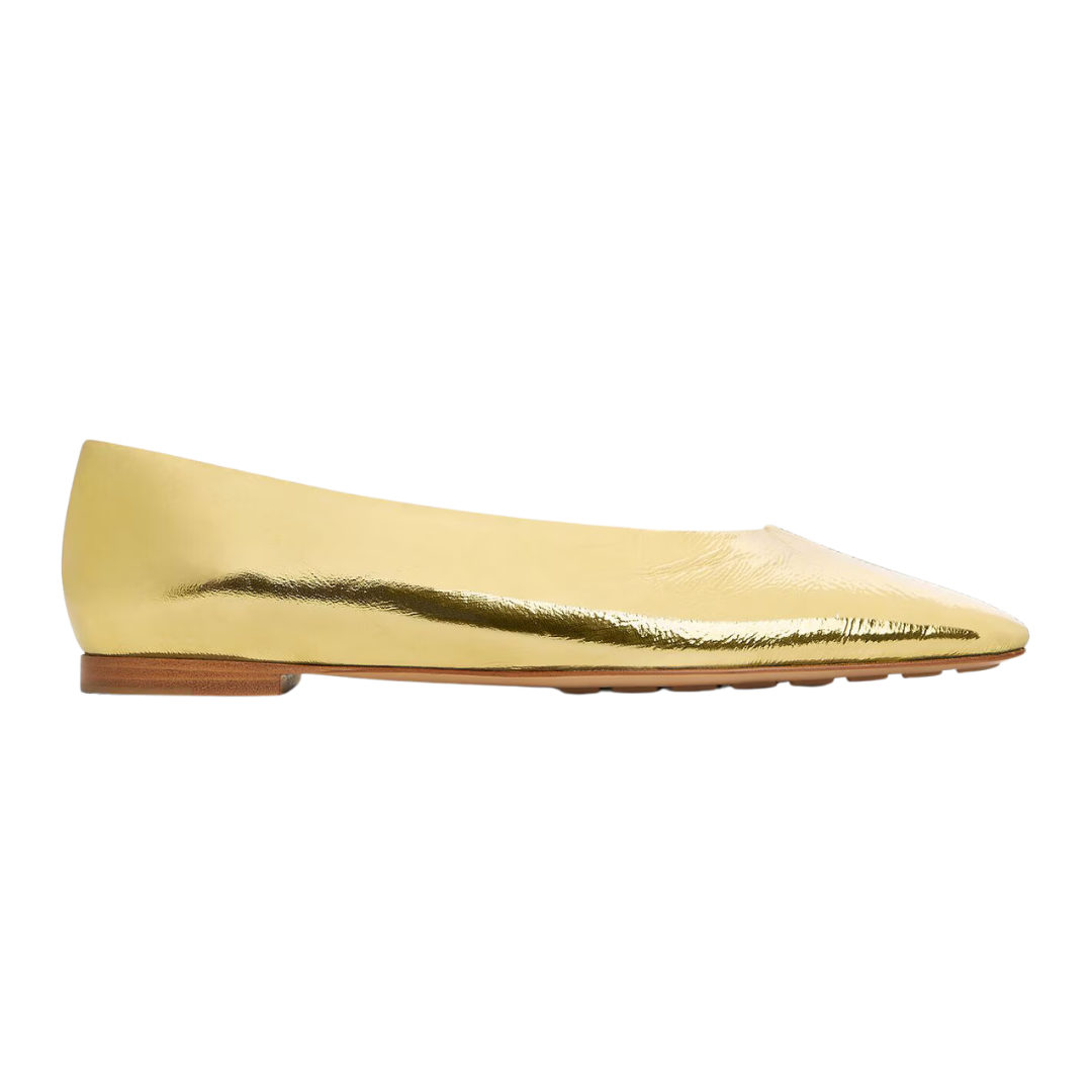 Gold flat shoe on a white background