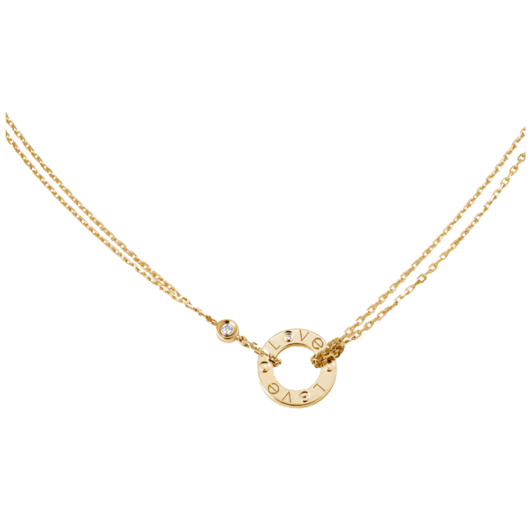 A delicate gold necklace featuring a central open circle pendant engraved with the letters 'LOVE' flanked by a small bezel-set clear stone and a tiny charm, on a plain white background.