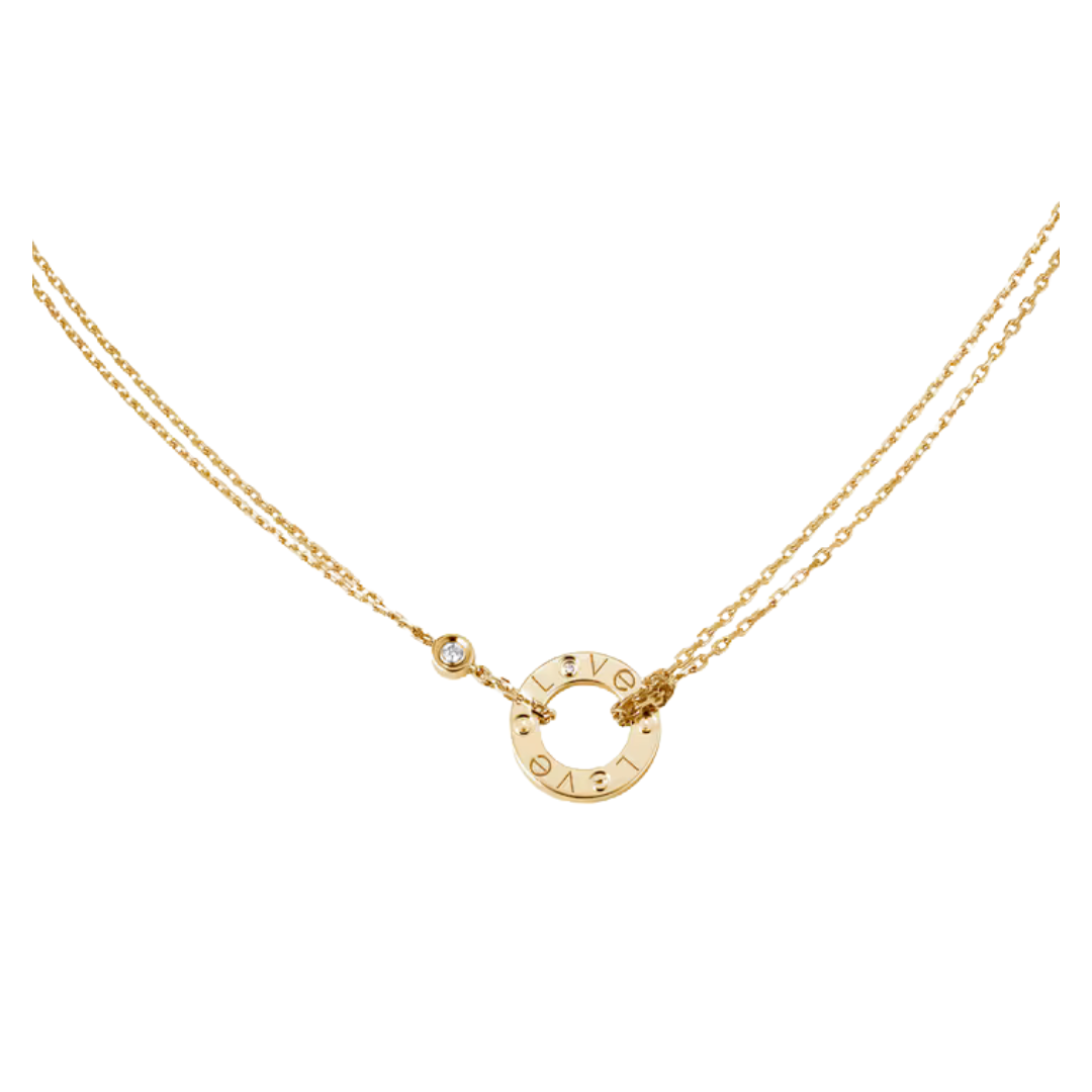 A gold double-strand necklace featuring a circular ring pendant engraved with the letters 'LOVE' in reverse, a small bezel-set clear stone, and a tiny gold flower charm, shown against a plain white background.