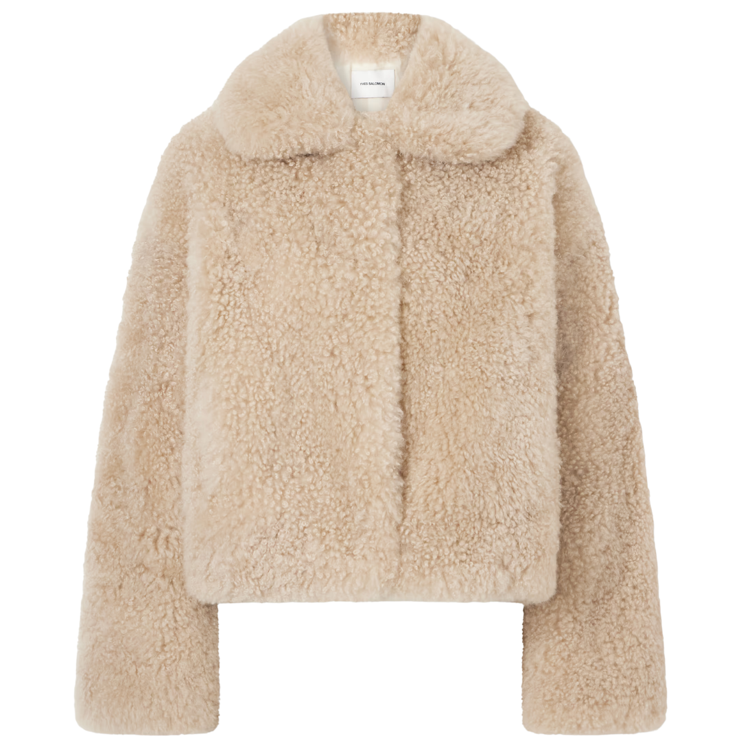 A cropped teddy fleece jacket in a warm beige color, featuring a wide collar and long sleeves, shown against a plain white background.